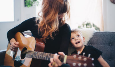 A candid portrait of a mother playing guitar and her son singing along